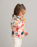 Child wearing a colorful floral jacket on a plain background